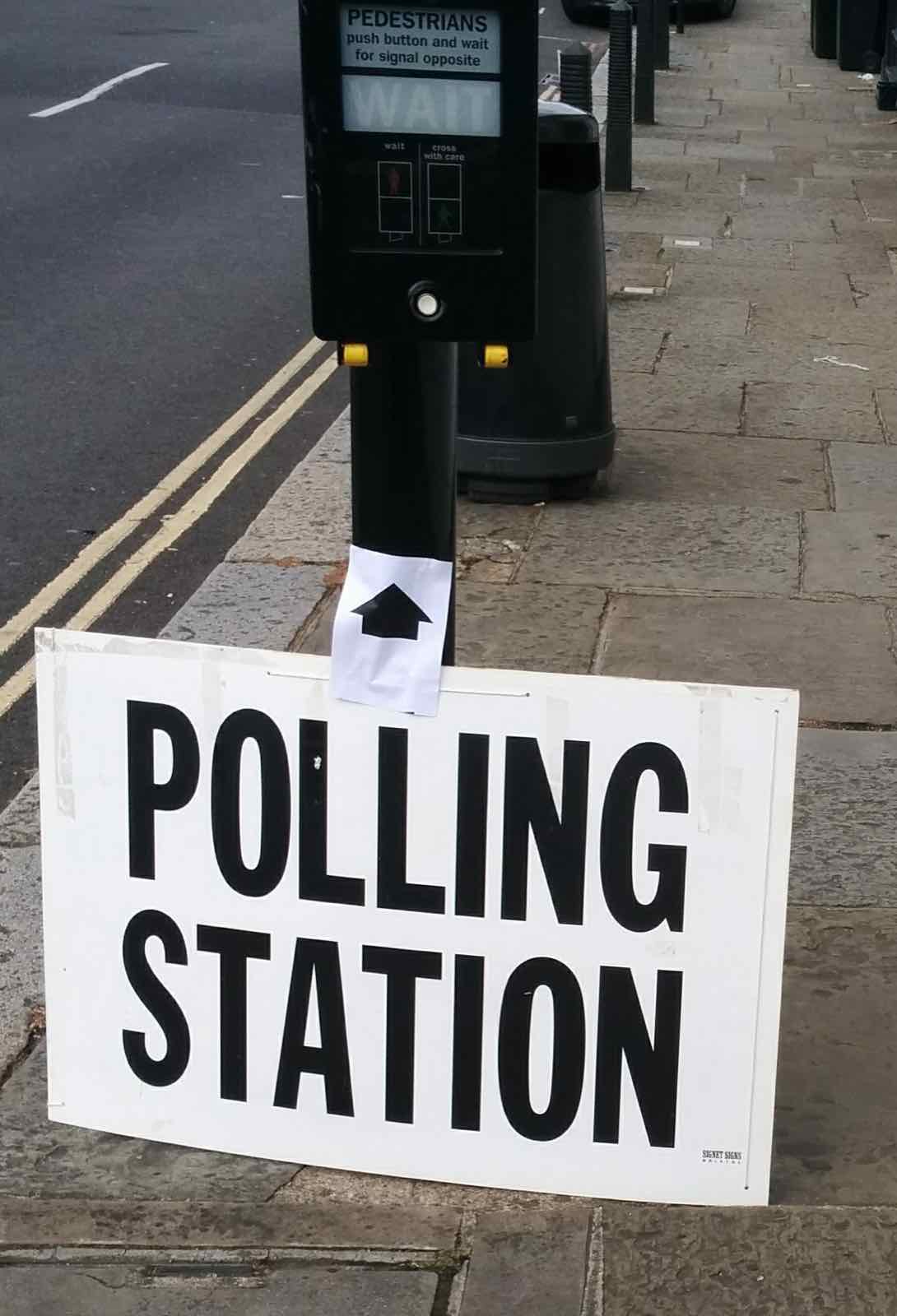 لندن کی ایک گلی میں Polling Station (پولنگ اسٹیشن) کا بورڈ، جو پولنگ اسٹیشن کی طرف راستہ دکھا رہا ہے