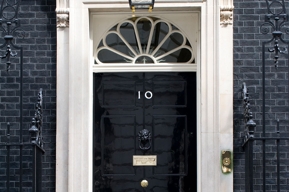 La porta d'ingresso nera del 10 di Downing Street, con il numero 10 bianco e un battente a testa di leone
